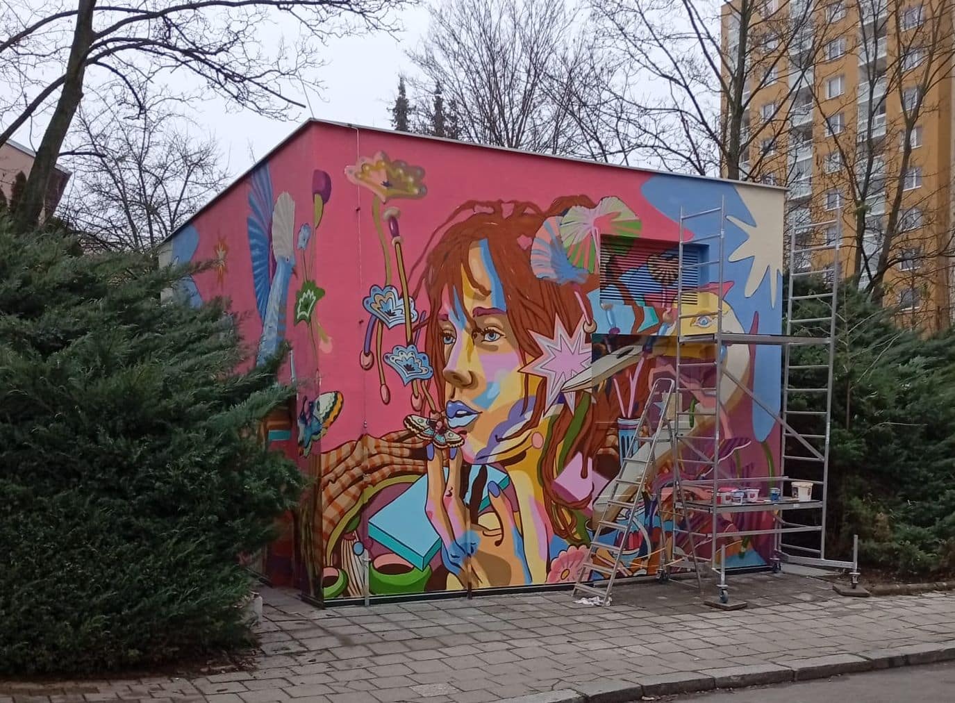 Francouzský umělec, dlouhodobě žijící v Česku, ztvárnil na stěnách trafostanice na rohu Horáckého náměstí a ulice Marie Hübnerové abstraktní motivy dívky, květin či volavky